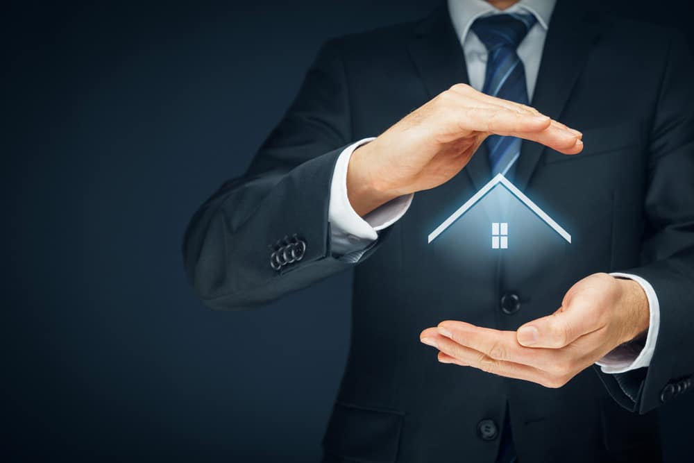 Un homme en costume tient une maison pour symboliser les investissements immobiliers